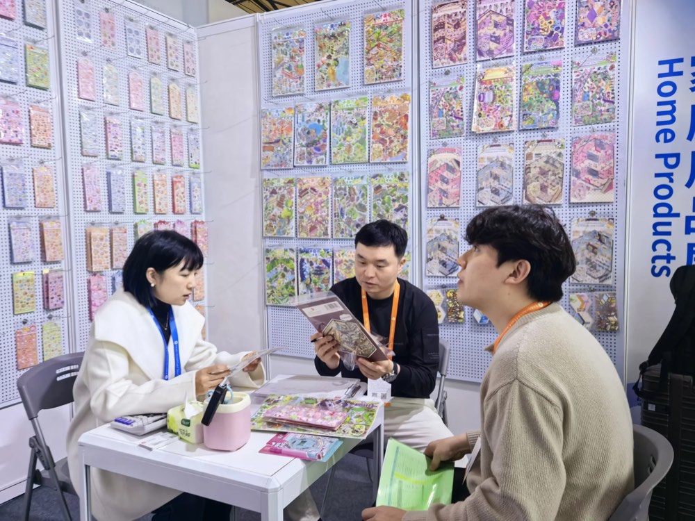 展示会ブースで製品サンプルを確認しながら商談する様子